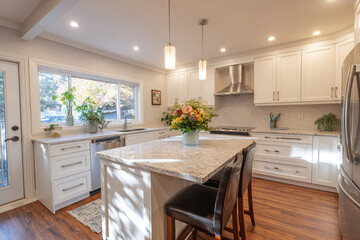Fototapeta premium Bright kitchen with island in center and window light casting shadows