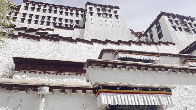 Establishing upward angle of Potala Palace in Lhasa with mountain backdrop under cloudy sky