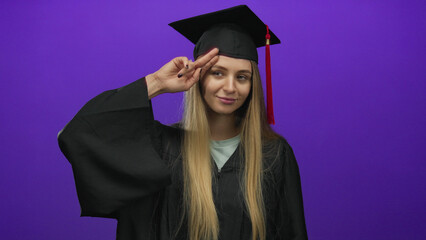 Young woman in graduation uniform posing confidently against an isolated purple background,...