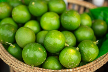 Group of fresh green lemon or lime in basket that selling at vegetable local market, object close-up with selective focus.