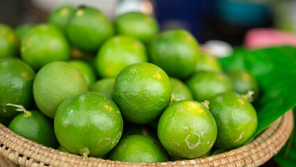Group of fresh green lemon or lime in basket that selling at vegetable local market, object close-up with selective focus.