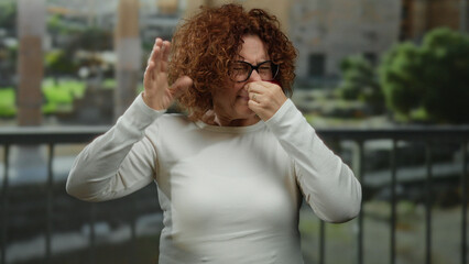 Woman reacting to bad odor on a city street with a disgusted expression, wearing glasses, with...