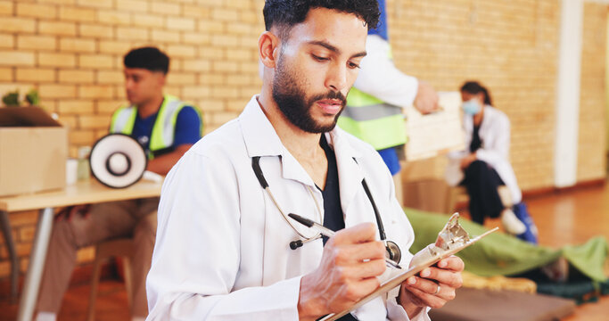 Doctor, man and writing on clipboard in community center for notes, charity or healthcare. Medical worker, checklist and serious employee at ngo for wellness outreach, humanitarian aid or volunteer