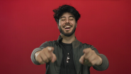 Young man with beard expressing happiness against red background, showcasing a cheerful and...