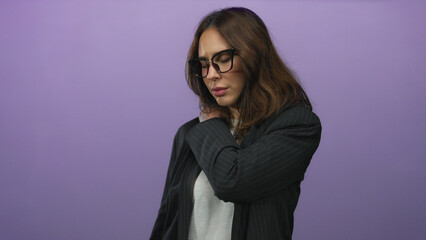 Young hispanic woman in glasses wearing a blazer over white shirt experiencing back pain against...