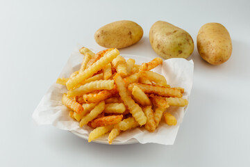 Crispy French Fries Served on White Plate with Fresh Potatoes for Side