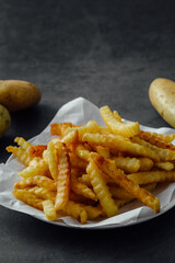Crispy French Fries Served on a White Plate with Potatoes in Background