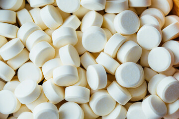 Close-up View of White Round Tablets Piled Together on Surface