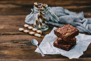 Delicious Brownies with Nuts and Chocolate Rolls on Rustic Background