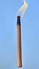 Smoldering Incense Stick Against a Blue Sky