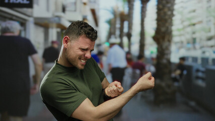 Young man making playful gesture outdoors on a bustling urban street showcasing lively city...