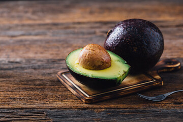 Fresh Avocado with Seed on Cutting Board Next to Whole Avocado