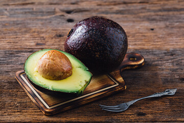 Fresh Avocado Halved with Seed on Wooden Cutting Board Background