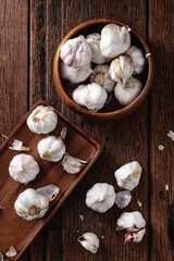 Fresh Garlic Bulbs in Wooden Bowl and Tray on Rustic Table