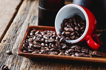 Freshly Roasted Coffee Beans Spilled from Red Cup on Rustic Table
