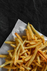 Crispy French Fries on White Paper with Dark Background
