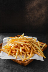 Crispy Golden French Fries on Wooden Platter with Dark Background