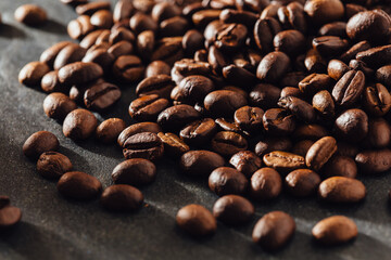 Freshly Roasted Coffee Beans Spilling on Dark Textured Surface