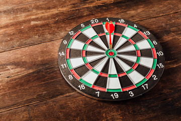 Dartboard with a Red Dart on Wooden Table Surface in Natural Light