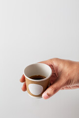 Hand Holding Small Coffee Cup Against Plain Background