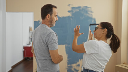 Hispanic couple discussing home renovation ideas in a cozy apartment living room, showcasing their love and connection while surrounded by paint samples and design inspiration.