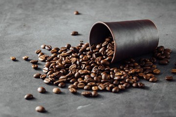 Brown Coffee Beans Spilled from a Black Cup on Dark Surface