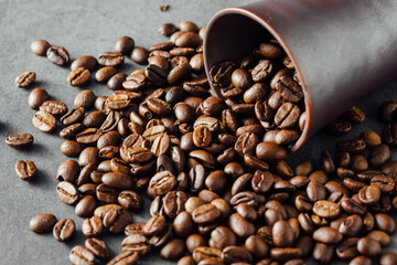 Fresh Roasted Coffee Beans Spilled From Copper Cup on Dark Surface