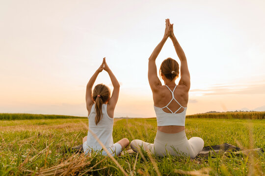 Mother and daughter practicing yoga poses in nature.