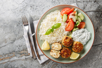 Delicious chicken meatballs stuffed with feta cheese served with lemon rice, tzatziki sauce and...