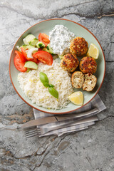 Greek chicken meatballs with feta cheese served with lemon rice and vegetable salad close-up in a...