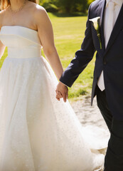 Close up of bride and groom holding hands and walking outdoors