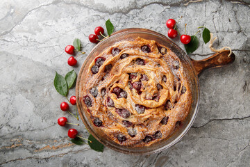 Sweet crispy filo pastry tart with cherries and custard close-up in glass bowl on wooden board....