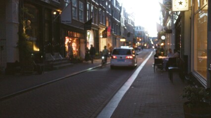 Blurred bustling european city street scene with pedestrians, bicycles, and cars, creating a dynamic atmosphere of urban life during daylight.