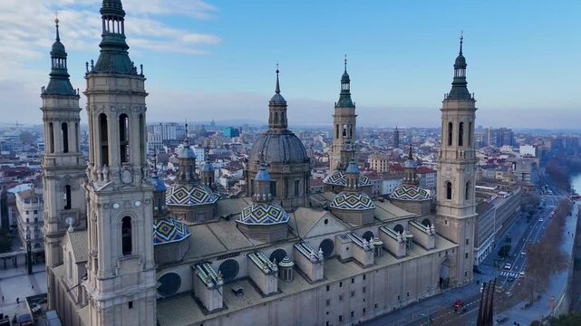 Aerial view of a historic cathedral with multiple domes and towers by a river in a cityscape.