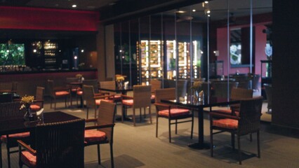 Blurred indoor restaurant scene with empty tables and chairs featuring a cozy atmosphere, warm...