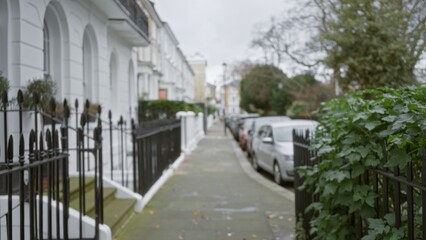 Blurry street view of a quiet chelsea neighborhood in london during winter, showcasing out-of-focus townhouses and parked cars under an overcast sky.