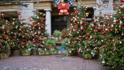 Defocused view of festive christmas decorations in covent garden, london, featuring blurred winter trees adorned with lights and ornaments in a charming, bokeh-filled street setting.