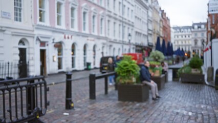 Blurred city street in london with people sitting and walking during winter in an out-of-focus...
