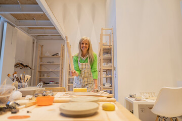 Ceramist preparing clay in workshop using rolling pin