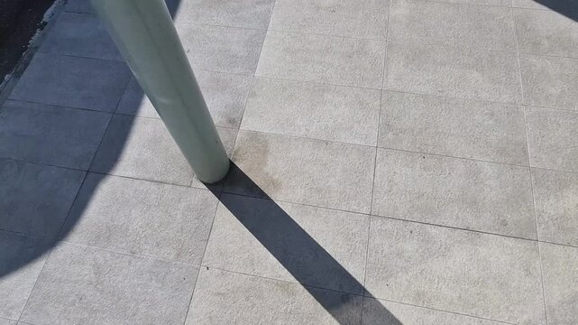 industrial mat cleaning zones at the entrance to the building. A black plastic-metal mat in the shape of an arch or half-circle lies on the limestone mosaic tiles