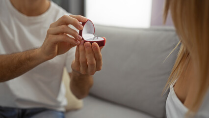 Man proposing to woman indoors with engagement ring, showing love and relationship in cozy home setting, highlighting romantic moment in living room with couple, together.