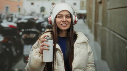 Woman in park wearing headphones and holding spray can, showcasing urban graffiti culture with...