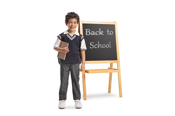 Asian schoolboy with a backpack and book in front of a blackboard