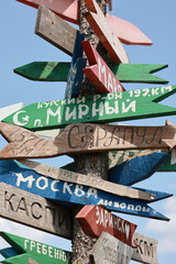 Close Up Of Multiple Colorful Wooden Arrow Signs With City Names In Cyrillic, Nailed To A Post On...