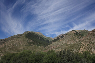 View Of A Mountain Range With Green Lower Slopes And Rocky Upper Parts, Under A Deep Blue Sky With...