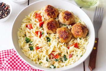 Orzo pasta with chicken meatballs, tomatoes and herbs. Italian food.