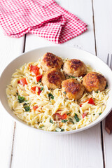 Orzo pasta with chicken meatballs, tomatoes and herbs. Italian food.