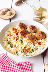 Orzo pasta with chicken meatballs, tomatoes and herbs. Italian food.