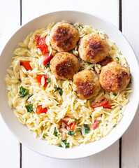 Orzo pasta with chicken meatballs, tomatoes and herbs. Italian food.