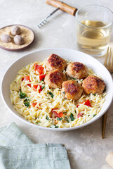 Orzo pasta with chicken meatballs, tomatoes and herbs. Italian food.